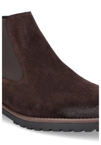 Brązowe zamszowe botki za kostkę z elastycznymi panelami bocznymi, zaokrąglonym noskiem oraz teksturowaną gumową podeszwą z kontrastowym brązowym wykończeniem.