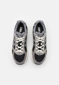 Grå och svarta sportskor med ovandel i mesh och mocka, vita snören, vadderad krage och logodetaljer på tungan och sido paneler.