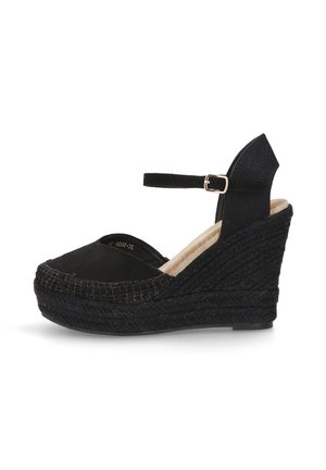 Zapato de esparto negro con cuña, con suela de yute trenzado, punta redondeada y correa en el tobillo. Parte superior de tela suave y detalles texturizados en el talón.