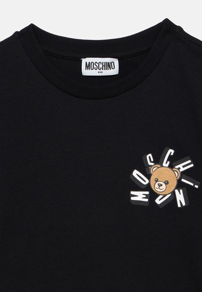 Μαύρο κοντομάνικο t-shirt με γραφικό αρκούδας και το κείμενο "MOSCHINO" σε έντονα, παιχνιδιάρικα γράμματα στ η αριστερή πλευρά.