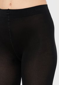 Svarte leggings med en glatt tekstur og en bred, elastisk midjebånd. Har en tettsittende design, laget av stretchbart materiale for komfort.