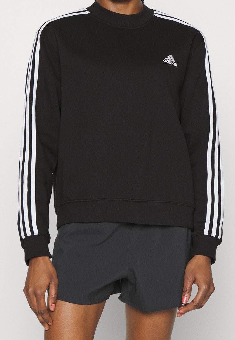 Svart sweatshirt med vit tre-stripsdesign på ärmarna, rundad hals, ribbade muddarna och liten Adidas-logotyp på bröstet.