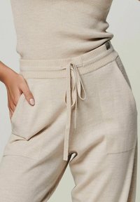 Beige Strick-Jogginghosen mit geripptem Bund, Kordelzug und Seitentaschen, die eine weiche Textur und eine lässige Passform bieten.