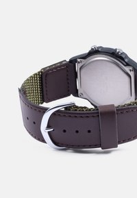 Pulseira de relógio de couro castanho com um forro de tecido verde texturizado, fivela prateada e fundo de caixa em aço inoxidável.
