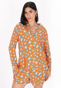 Orange pyjamasset med en knapp-up, långärmad topp och shorts med ett blått och rosa leopardmönster. Mjuk, lätt tyg.