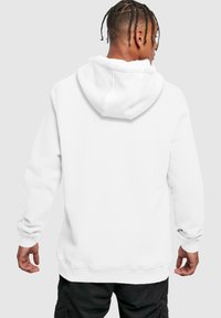 Hvid hoodie med en blød tekstur, snøre i hætten og ribbede manchetter. Har en afslappet pasform og kengurulomme foran.