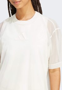 Witte sportieve shirt met raglan mesh mouwen, een ronde hals en een tonale drie-strepen logo op de borst, met een gladde stoftextuur.