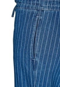 Džínsy s vertikálnym prúžkovým vzorom v tmavomodrej a bielej farbe. Obsahujú elastický pás so šnúrkou a bočnú kapsu.