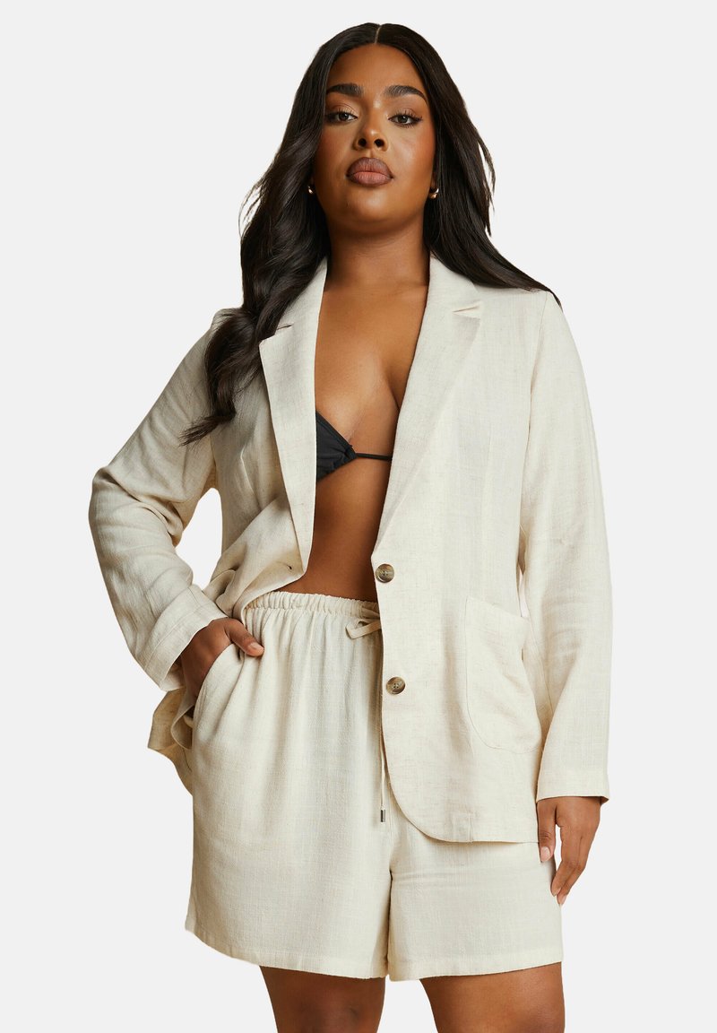 Beige linn blazer med två knappar, sidofickor och matchande dragsko-shorts. Texturerad tyg, avslappnad design, öppen frontstil.