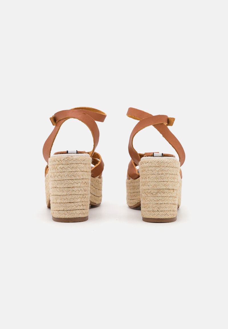 Sandalias de tacón alto de cuero marrón con plataforma de yute trenzado, que cuentan con tiras cruzadas en el tobillo y un tacón texturizado.