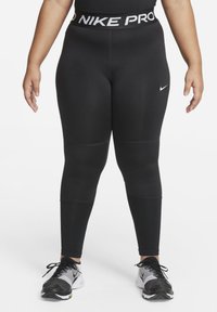 Schwarze Nike Pro Leggings mit einem breiten Taillenbund, der mit weißem Branding versehen ist. Gefertigt aus dehnbarem Stoff mit glatter Textur und figurbetontem Design.