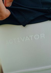Uno strato di tessuto nero strutturato sopra un tessuto bianco liscio. La parola "ACTIVATOR" è impressa in bianco nella sezione inferiore.