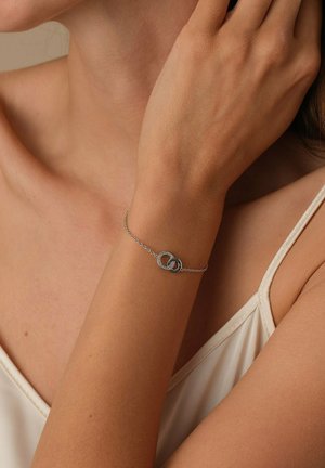 Silberne Kettenarmband mit miteinander verbundenen runden Akzenten, einer strukturiert und der andere glatt, auf einem nackten Handgelenk präsentiert.