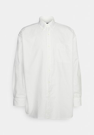 Chemise blanche à manches longues avec boutons, en coton. Comprend un col, une poche avant et des détails en boutons le long de la patte de boutonnage et des poignets.