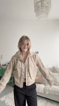 Smėlio spalvos trumpa striukė su aukštu apykakliu, priekyje sagomis ir gofruotomis rankogaliais. Dėvima ant baltos palaidinės ir derinama su juodomis kelnėmis.