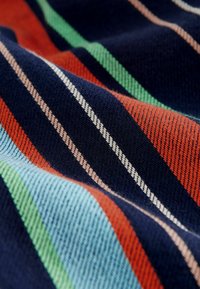 Tessuto multicolore con strisce in blu navy, arancione, verde e azzurro pallido, caratterizzato da texture contrastanti e dettagli di tessitura fine.