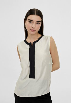 Blusa sin mangas en tejido crema con un panel vertical negro y cuello. Textura suave, corte relajado y diseño simple. Sin adornos.