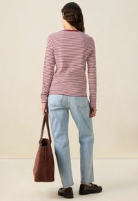 Langärmliges gestreiftes Oberteil in Dunkelrot und Weiß, lässige Passform. Kombiniert mit hellblauen Jeans, brauner Wildleder-Tasche und dunklen Schuhen.