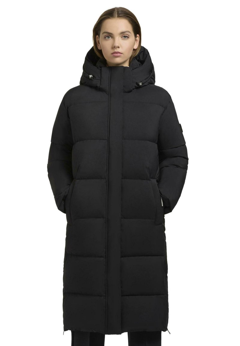 Cappotto puffa nero con silhouette lunga e adatta, texture trapuntata, cappuccio e tasche laterali. Presenta una cerniera frontale e chiusure a scatto.