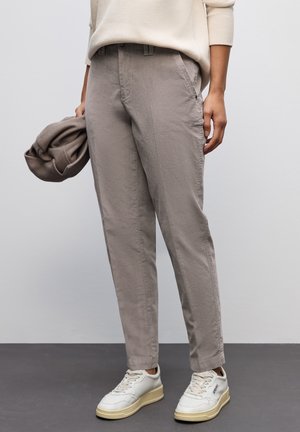 Lichtbeige katoenen broeken met een tapered fit, voorzien van zijzakken en een gladde textuur, in combinatie met witte sneakers.