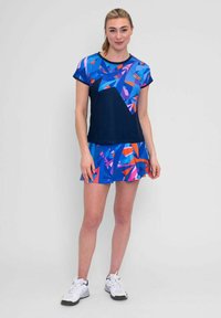 Conjunto deportivo en azul y morado con patrones geométricos. Diseño de camiseta de manga corta y falda. Fabricado en tejido ligero y elástico.