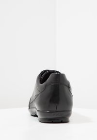 Pantof black din piele cu o textură netedă, vârful rotund și cusături minime. Dispune de o talpă din cauciuc și un logo debossat pe toc.