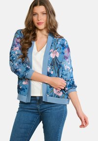 Ziedu bombere jaka zilā krāsā ar rozā un zaļām akcentiem. Mīksts audums, riboti aproces un apakšmala, atvērta priekšpuse un elkoņa garuma piedurknes.