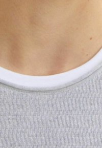 Szara strukturalna koszula z białym okrągłym dekoltem, ukazująca kołnierz i górną część klatki piersiowej, bez dodatkowych wzorów czy zdobień.