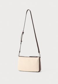 Borsa a spalla in tela beige con tracolla in pelle marrone. Forma rettangolare, dotata di chiusura con zip e design minimalista.