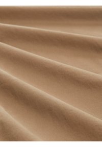 Hladká béžová tkanina s jemnými záhyby a jemným diagonálním vzorem, rovnoměrně osvětlená s podmanivými stíny, které zvýrazňují texturu.