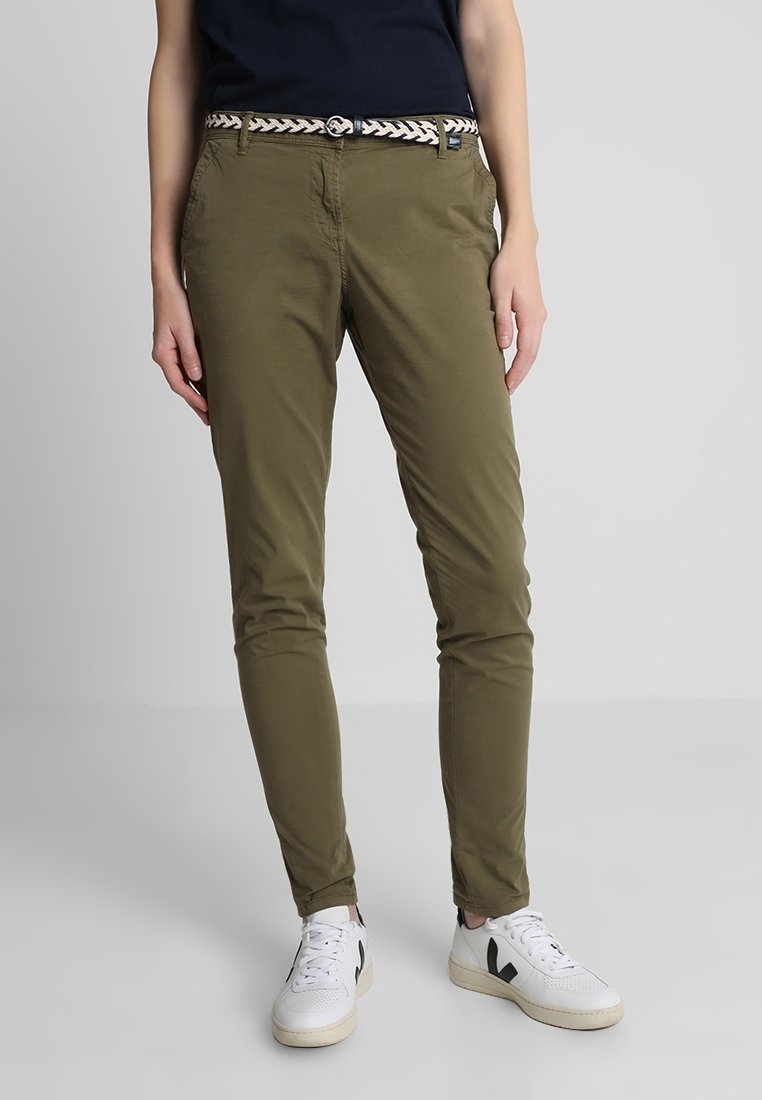 Olivgrön chinos med slim fit, sidofickor och ett vävt svart och vitt bälte. I hop med vita sneakers.