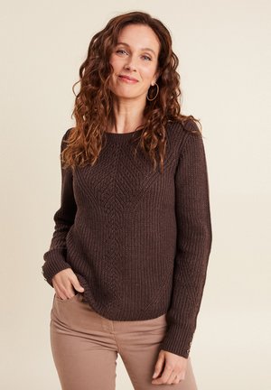 Bruin gebreid sweater met een gestructureerd ruitpatroon, lange mouwen en knoopaccenten op de manchetten, gedragen over beige broek.