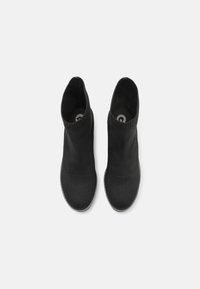 Bottes noires à lacets avec un dessus en tricot, texture lisse et col élastique. Bout rond et semelle plate pour le confort et la stabilité.