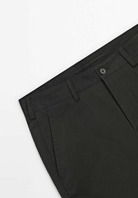 Pantalon noir en tissu lisse, doté d'une fermeture à bouton, de poches latérales et d'une coupe ajustée avec un design avant plat.