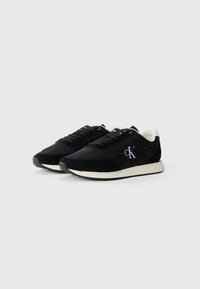 Zwarte sportieve schoenen met bovenwerk van nubuck en textiel, witte tussenzool en geborduurd logo aan de zijkant. Veters ontwerp met een gevoerde kraag.