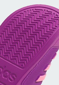 Fioletowa guma podeszwy trampka z wzorem bieżnika w formie zygzaka, z teksturowaną powierzchnią i różowym akcentem wzdłuż boku.