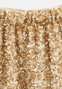 Zlatá flitrová látka so zoskupeným elastickým horným lemom, zdobená lesklými, okrúhlymi flitrami pokrývajúcimi mäkký, béžový podklad.