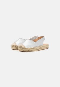 Espadrillas metalliche argento con punta rotonda, suola in corda di juta e design a schiena aperta. Texture liscia con dettagli di cucitura minimi.