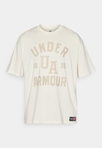 Krämfärgad bomullströja med korta ärmar som har "UNDER ARMOUR" och "1996" i stora beige blockbokstäver. Märkesskylt vid sidsömmen.