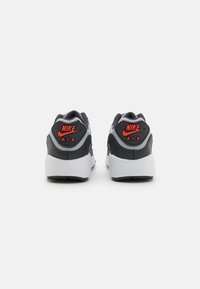 Nike Air αθλητικά παπούτσια με μαύρο και γκρι επάνω μέρος, κόκκινες λεπτομέρειες στο λογότυπο, μαλακό κολάρο και λευκή σόλα. Διαθέτουν υφή στη �φτέρνα και καουτσούκ σόλα.