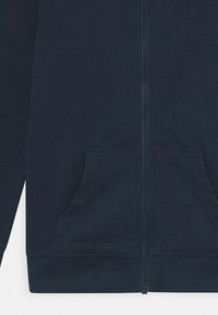 Felpa con zip di colore blu navy, realizzata in morbido cotone, con zip anteriore, due tasche laterali e polsini e orlo a coste.