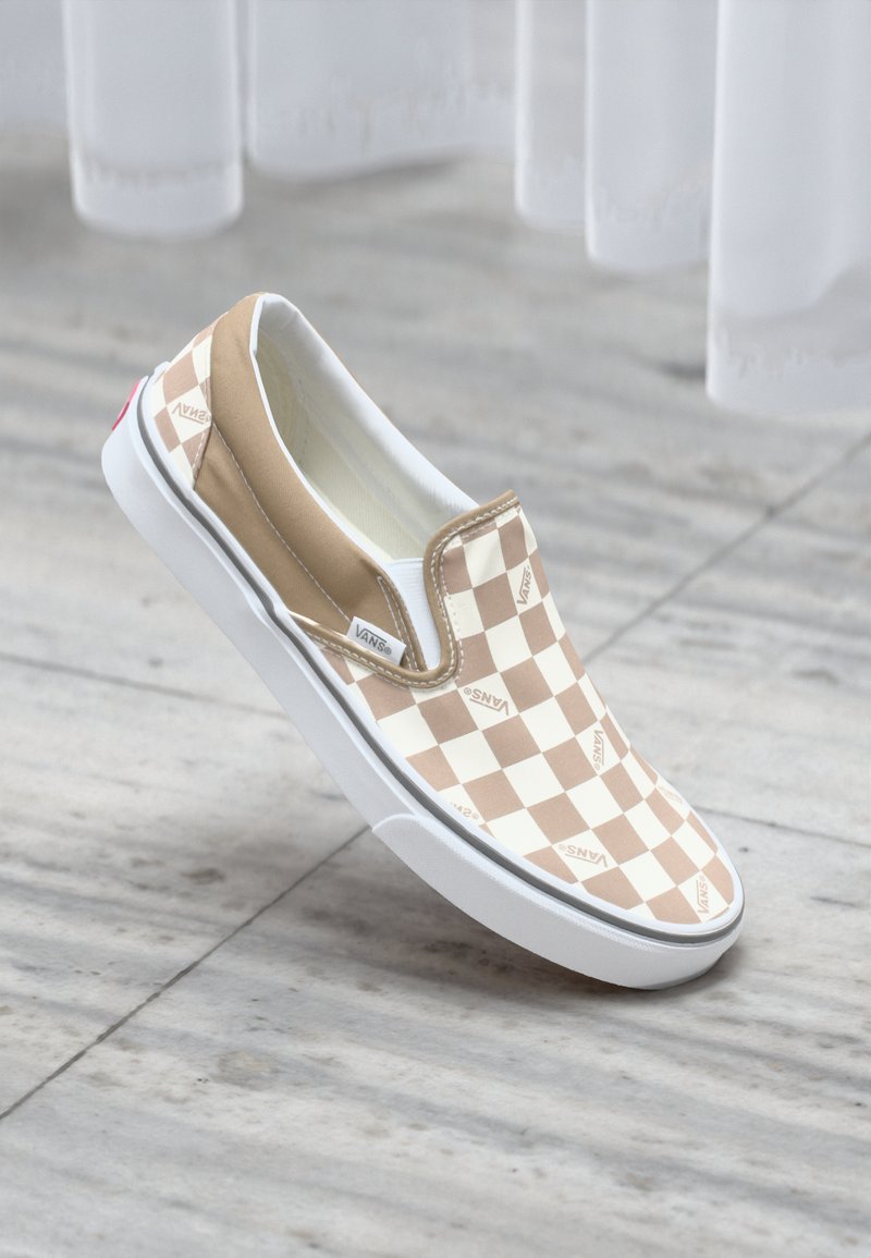 Bež i bijeli karirani slip-on Vans tenisice s bijelim gumeni potplat i malim crvenim naglaskom na peti. Glatka tekstura tkanine.