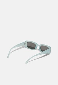 Une paire de lunettes de soleil rectangulaires bleu clair avec des verres foncés, présentant une finition brillante et des branches effilées et fines.