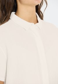 Witte, kortarmige shirt met een kraag en knoopsluiting. Gemaakt van lichtgewicht, gestructureerde stof met een subtiele kreukelige uitstraling.