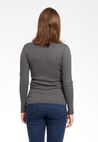 Maglia grigia a maniche lunghe realizzata in un materiale morbido e elastico, abbinata a jeans aderenti blu scuro. La vista posteriore mostra un design semplice e sinuoso.