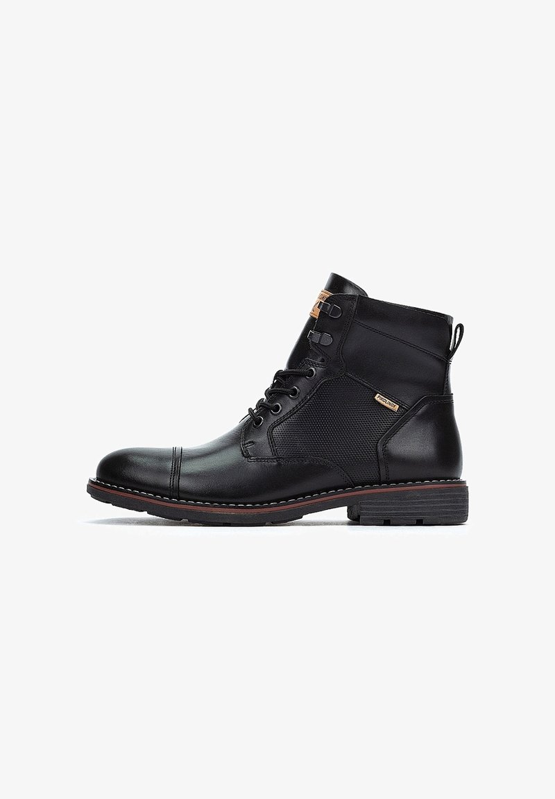 Bottine noire en cuir à lacets avec bout renforcé cousu, panneau latéral texturé, languette au talon et talon bas empilé sur fond blanc.