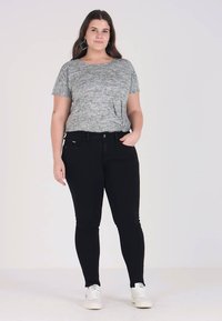 Gray textured short-sleeve t-shirt paired with slim-fit black jeans and white sneakers. Fashionable accessories include turquoise earrings.
