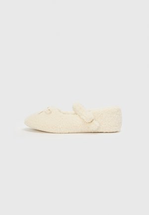 Cream-colored slipper with a fuzzy texture, flat design, rounded toe, and a decorative strap with a small accent.
