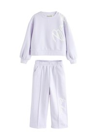 Lilla to-delt sæt bestående af en cropped sweatshirt med lange ærmer og en elastisk talje på breddebenede bukser, begge med hvide tekstdetaljer.