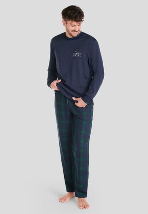 Camisa de manga larga de color navy con estampado "INVIERNO" y pantalones de pijama informales a cuadros en verde oscuro y azul con patrón de cuadros grandes.